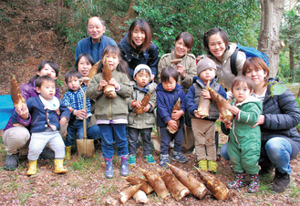 掘ったタケノコを持つ親子とすくすくサロンの福田代表（後列左）