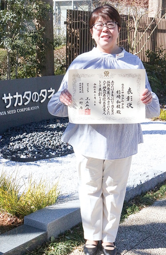 本社前で賞状を手にする杉崎さん