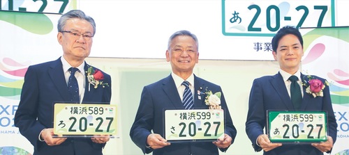 特別仕様のナンバープレートを手にする（左から）河村事務総長、高橋副大臣、山中市長
