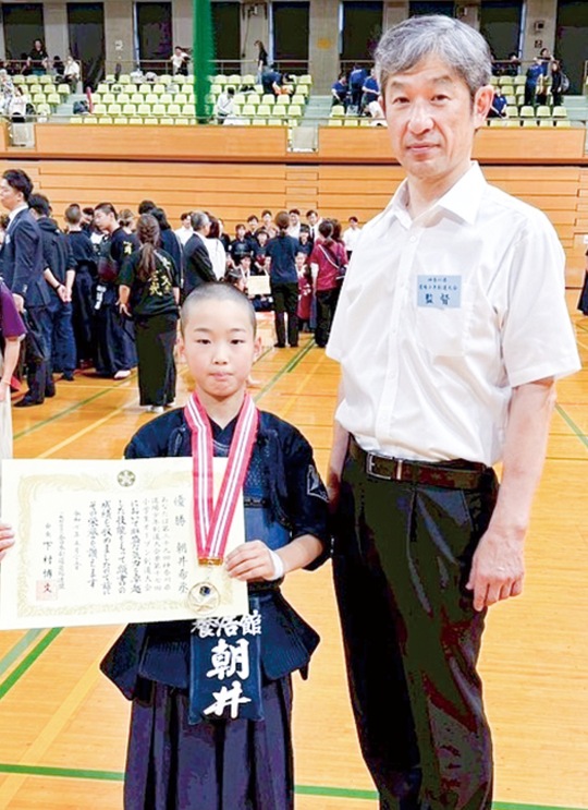 表彰状を持つ朝井さんと教え子の優勝を喜ぶ櫻井さん