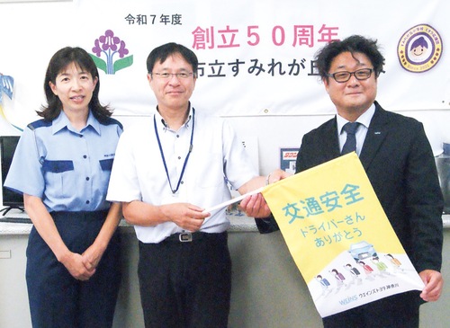 横断旗を持つ善甫執行役員（右）と栗原校長（中央）