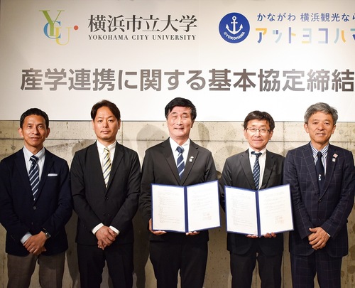 協定書を手にする横浜市大の石川学長（中央）と、アットヨコハマの山内取締役（右隣）