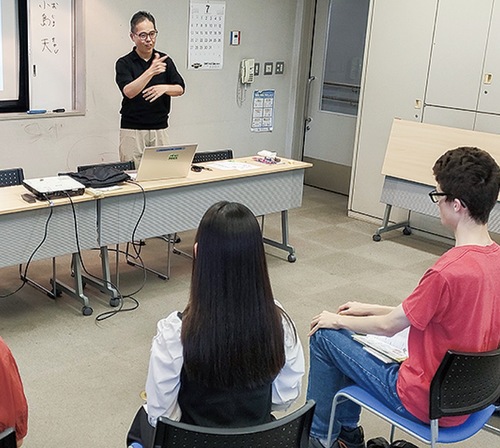 手話講座であいさつする市聴覚障害者協会の小島理事長（左奥）