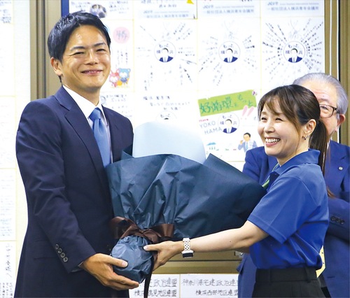 当選確実が報じられ花束を受け取る山中氏（８月３日、中区）