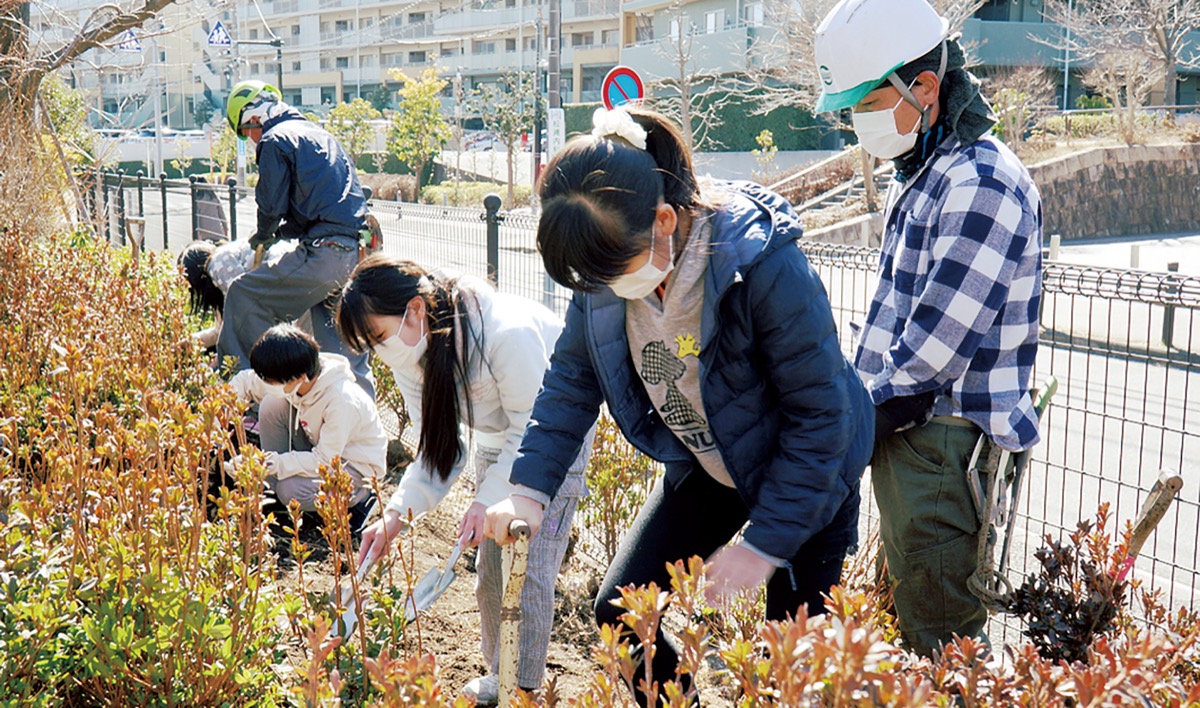 手ほどきを受けながらツツジを植える児童