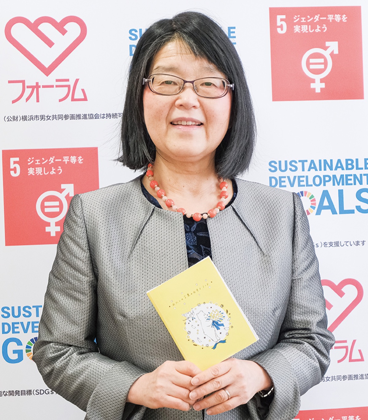 「わたしの言葉のお守りノート」を手にする田雑理事長