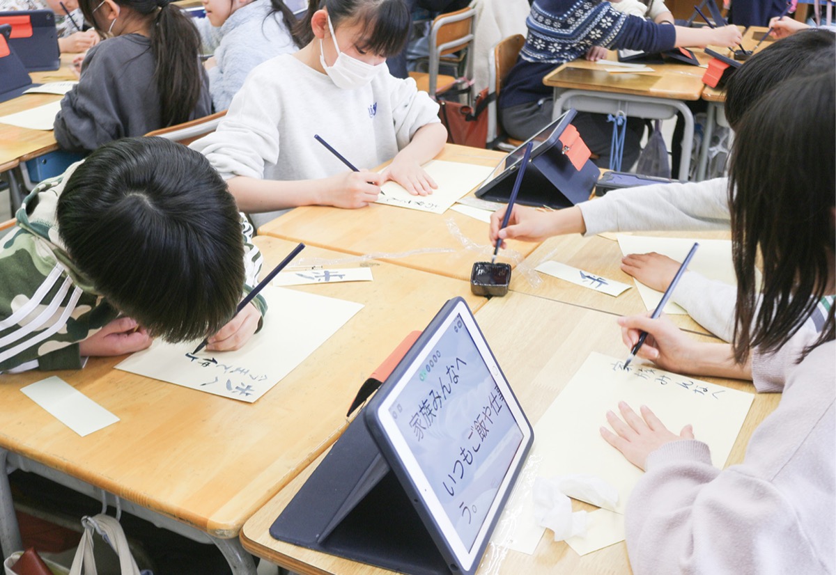 筆を使って感謝の思いを書く児童ら