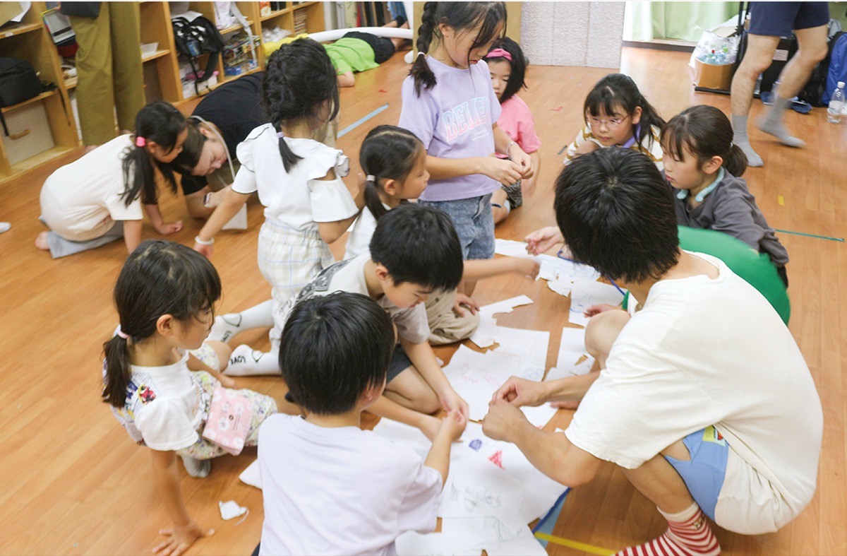 それぞれが描いた絵をちぎって1つの絵にする子どもたち