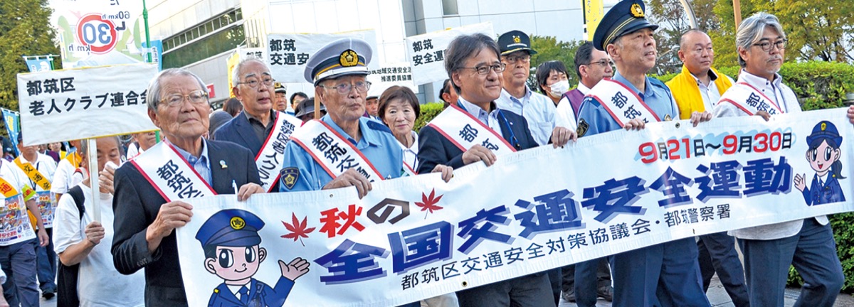 パレードで横断幕を手に歩く扇山署長（前列右から２人目）、佐々田区長（同３人目）ら