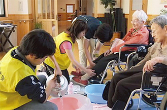 岩手県大槌町で高齢者の足浴を手伝う明学大生（6月18日）