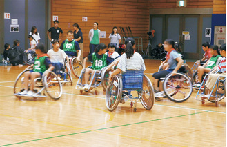 車いすバスケットボールを体験する児童ら＝旭区役所提供