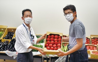 トマトを手渡す村田部長（右）