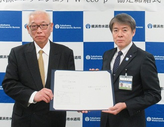 山岡秀一水道局長と協定書を持つ河野社長(左)