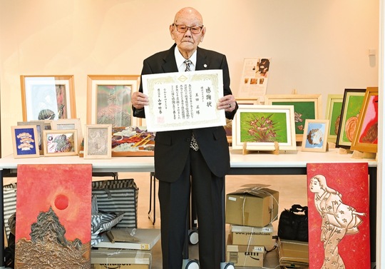 自身の作品の前で感謝状を手にする玉田さん