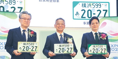 特別仕様のナンバープレートを手にする（左から）河村事務総長、高橋副大臣、山中市長