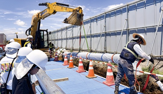 水道管の埋設を興味深く見守る児童たち