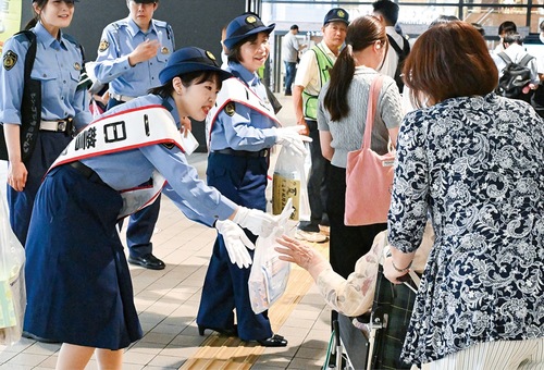 通行人に啓発物品を配る、大橋さん（手前左）と早川さん（中央）