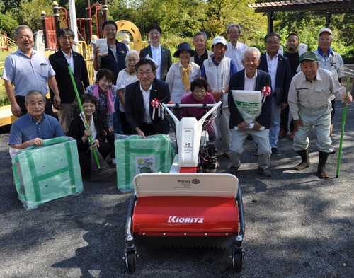 寄贈された草刈り機と両団体のメンバーら