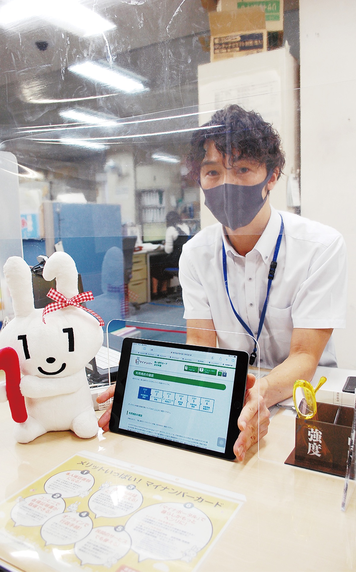 窓口でタブレット端末を手にする区戸籍課職員