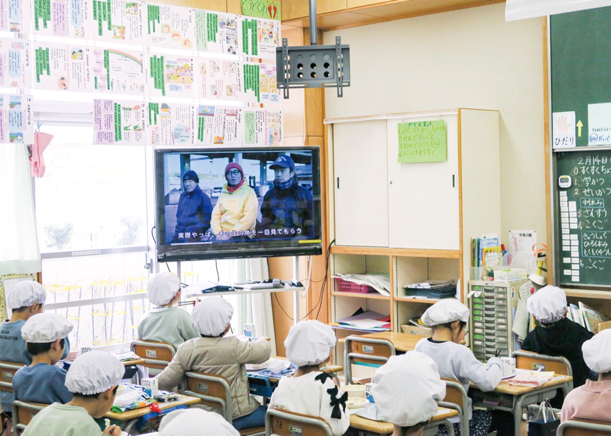 動画を見ながら給食を食べる児童