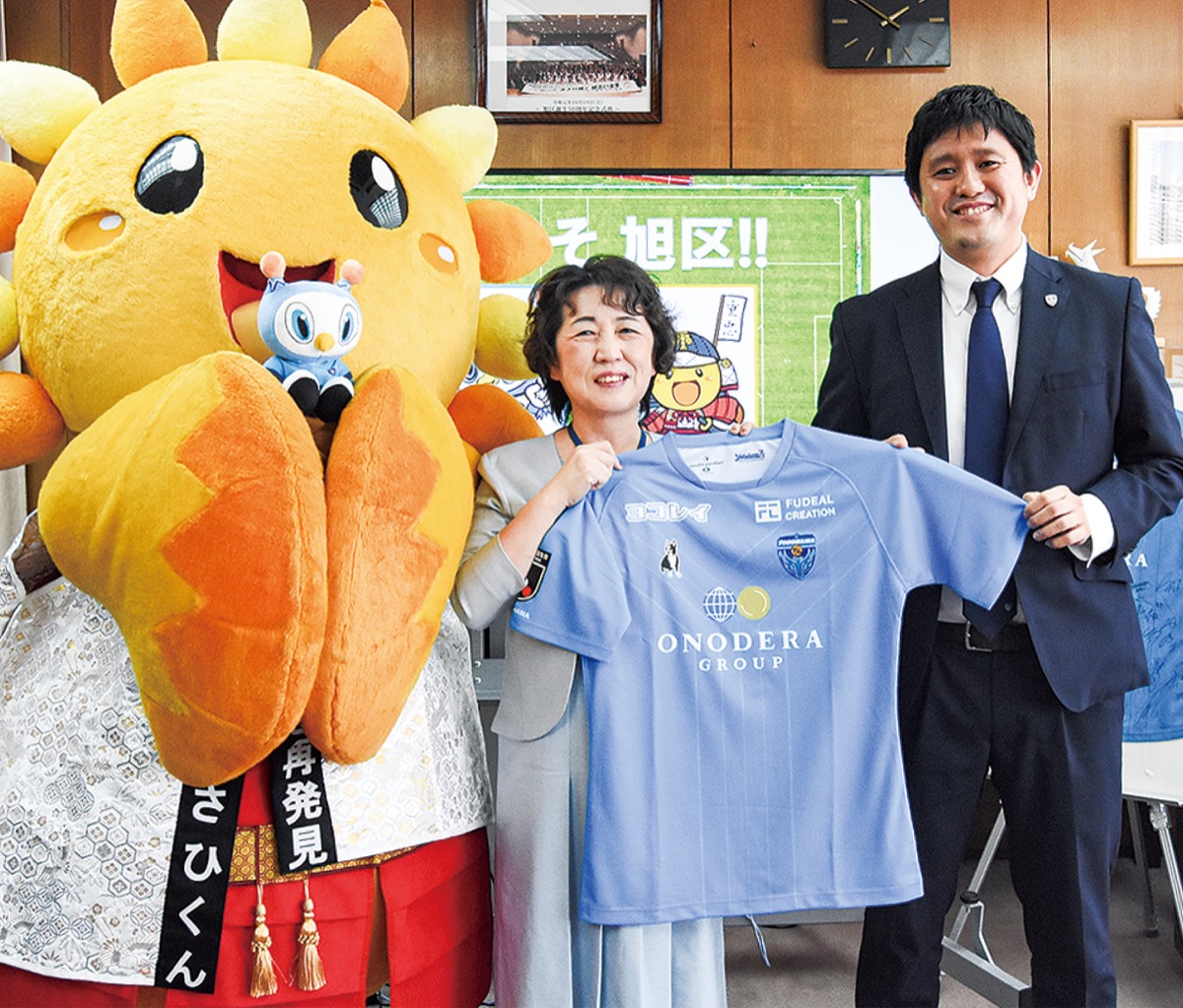 新ユニフォームを持つ権藤区長（中央）と木村ＣＯＯ