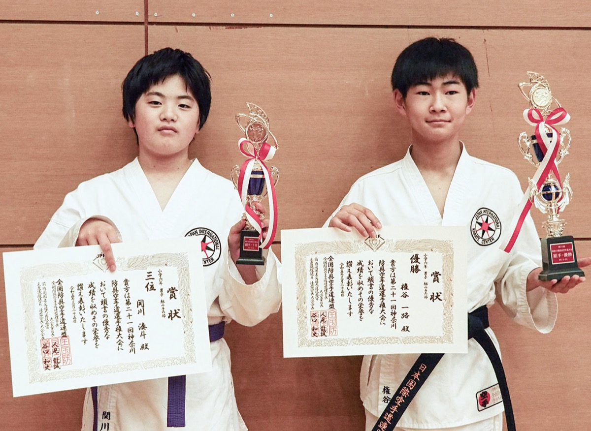 トロフィーと賞状をもつ２人