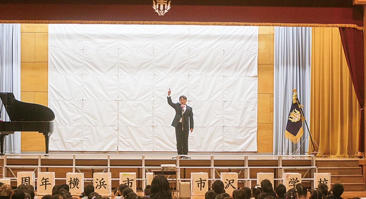 １５０周年記念実行委員会から贈られた電動式緞帳について紹介する江野澤校長