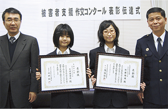 受賞を喜んだ久保さん（左から２番目）と佐藤さん（右から２番目）。山本義明瀬谷署長（右）から手渡された賞状を手に