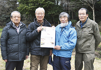 連載１回目の掲載紙面を持つ、執筆中心メンバーの（左から）清水道夫さん、今野紀昭さん、宮島代表、中村多加夫さん