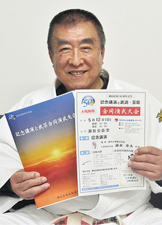 合同演武大会のポスターとパンフレットを持つ伊藤会長