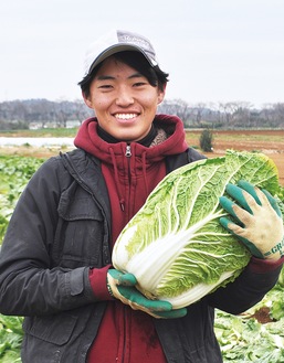 収穫した白菜を手に笑顔の秋山さん
