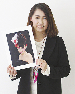 受賞作品の写真を手に笑顔の寉田采奈さん（20）