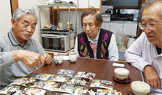 夏祭りの写真を見て目を細める秋山さん（左）と典子さん、岸さん