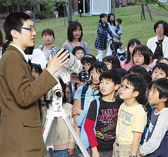 望遠鏡の解説をする篠原部長（左）と真剣に話を聞く子どもたち