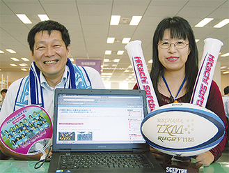 各チームの応援グッズを並べて開設したホームページをPRする地域振興課の岩崎さん（左）と古尾谷さん