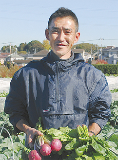 泉区の畑で野菜を手にする吉田さん。栽培から収穫、配達までをほぼ１人で行う