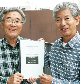 ２０周年の記念誌を手にする、根岸代表（左）と塚田幹夫副代表。市地域有形民俗文化財に登録されている、下倉田町の南谷の「大わらじ」も見学した