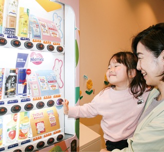 子育て応援ルーム「とことこ」横に設置された自販機でおむつを買う親子