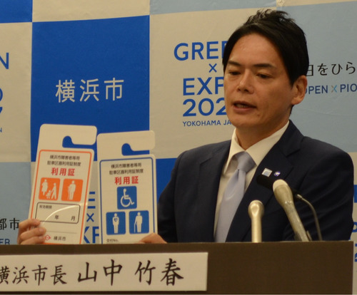 会見で利用証を手にする山中市長