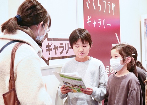 来庁者に冊子を手渡す児童