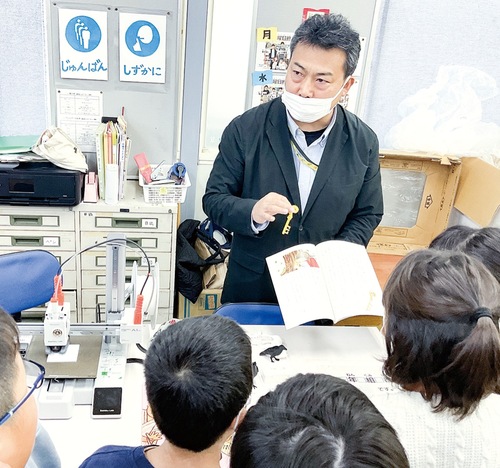 ３Dプリンターで作成した模型を見学する児童と解説する元木教授