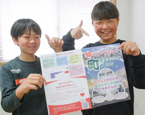 リーフレットを持ち笑顔の児童