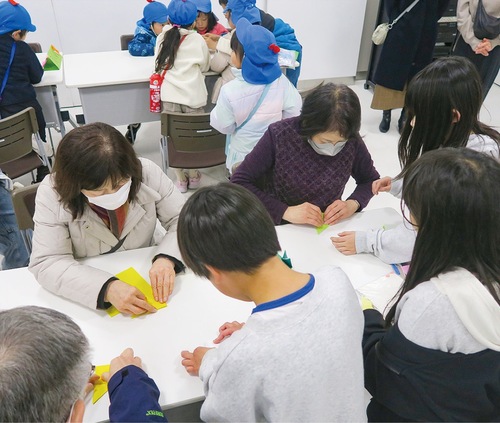 参加者に折り紙を教える児童（提供）