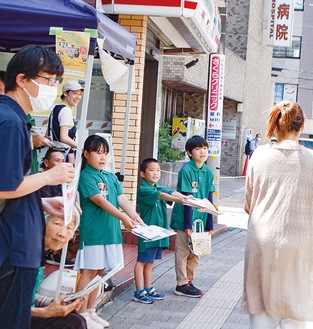 新聞エコバッグを配布する利用者と児童ら