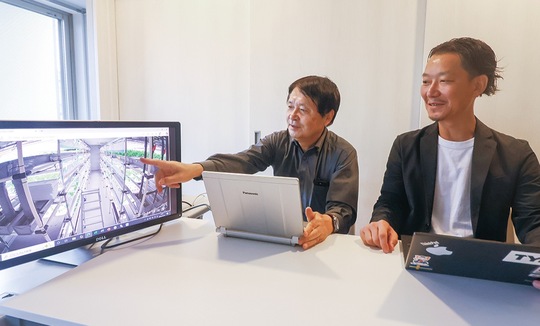 工場内を映すカメラの映像を解説する後藤代表（左）と鈴木課長