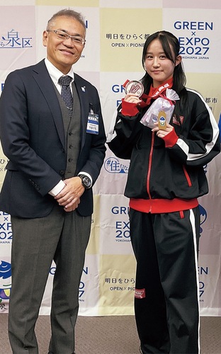 世界大会の銀メダルを持って笑顔の石井さん（右）と山口区長