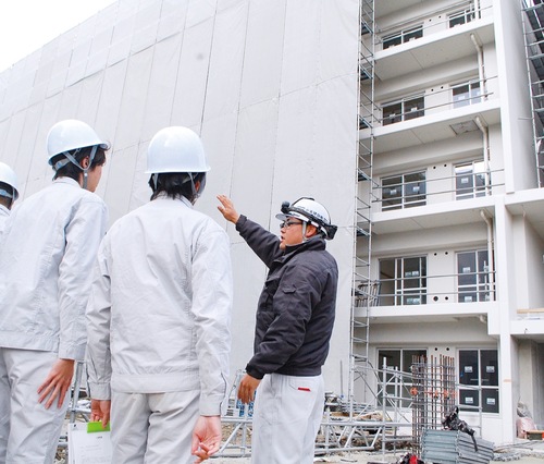 工事現場を案内する社員（右）と話を聞く生徒