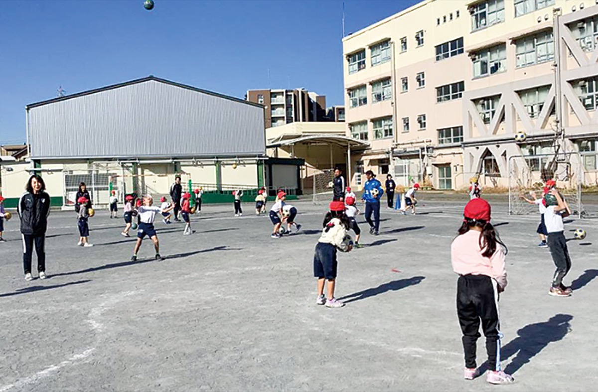 青空の下、体を動かす児童たち