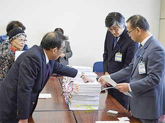 市長宛ての陳情書と署名を坂和伸賢建築局長（手前右）に手渡す山仲代表（同左）