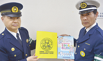 カバーを手にする栄警察署の小森安晃署長（左）と栄交通安全協会の森会長